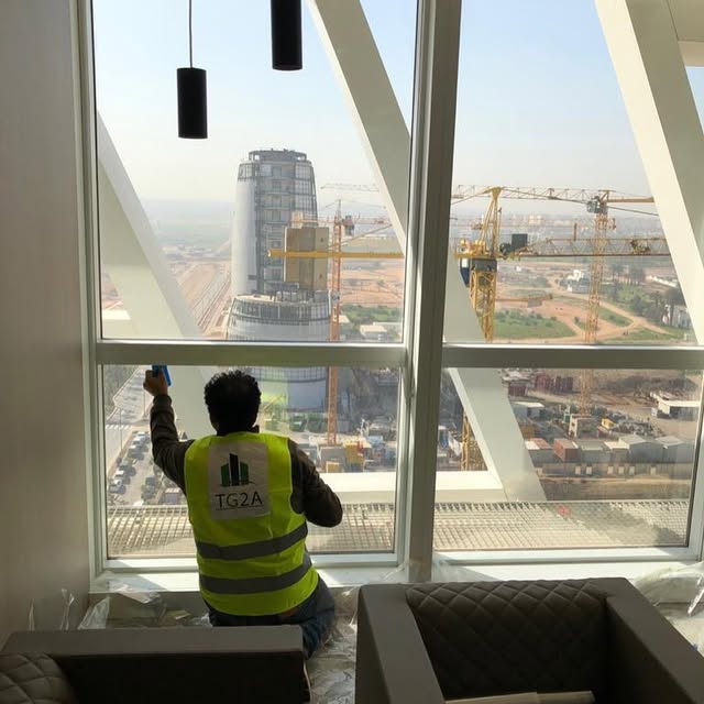 Technicien TG2A posant un film solaire sur une baie vitrée