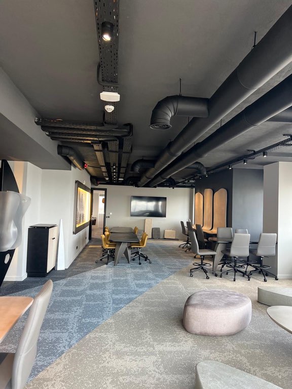 Espace collaboratif de bureaux avec réseaux apparents peints en noir et moquette dalles, réalisation TG2A 23